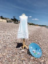 A beautiful white vintage sundress is shown on a beach