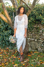 A beautiful model stands in a shaft of autumnal evening light , wearing a white cotton lawn Edwardian antique dress with Bedfordshire lace, broderie cut work, tape work and hand embroidered details. A crown of leaves and pastel rose bouquet complete the look.