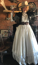Cowgirl bride! A floor sweeping lace and satin edwardian wedding gown is teamed with a battered buff coloured cowgirl hat, antique lace shawl, brown leather corset belt and cowboy whip. 