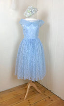 A pale blue vintage lace dress from the 1950's is shown on a dressmakers dummy, with a hat made of silk hydrangeas