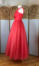 Side view showing the nipped in waist and full skirt of a fifties prom dress style gown in red organza