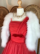 Styled shot of a red fifties dress with a fuax fur white bolero and pearls 