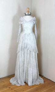 Shimmering vintage wedding gown in ivory lace with silver pewter threadwork, with a shawl collar , pelmet train and long sleeves