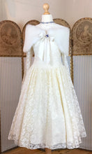 A 1950's wedding dress is shown with a feathered cap and blue paste brooch and necklace. The dress is a prom dress shape.