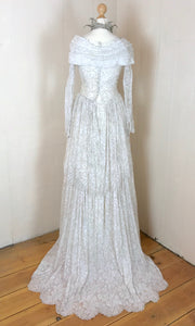 The back of a 1950's wedding dress in ivory lace with silver threadwork. the back view shows the beautiful lace train 