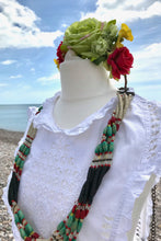 A white vintage summer dress is shown teamed with a Moroccan belt worn as a a necklace and a green and red flowercrown. the effect is very Bohemian  