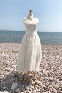 beautiful vintage wedding dress in ivory flocked organza, photographed on a pebble beach 