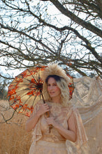 A beautiful blonde boho bride wears a dramatic, floor sweeping 1970's wedding dress made with gold lace in a floral pattern. She carries a beautiful vintage parasol which gives a festival feel to the look