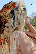 The spokes of a vintage parasol are visible. the parasol is held by boho bride