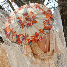 A backview of a bride showing her open parasol and backless vintage dress
