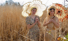 Prairie princesses! Models Josie and Jenny stand in a field of shoulder high golden grasses and reeds. Both carry golden parasols and wear vintage gowns - Josie is in a 1940's summer dress with a paisley print 