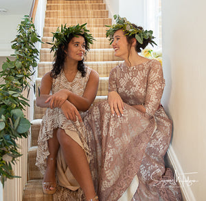 An English country house wedding scene showing two girls in green leaf crowns and vintage lace wedding dresses sat on the sweeping stairs of a charming country house. Country wedding inspiration  