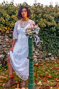 A beautiful model stands in a shaft of autumnal evening light , wearing a white cotton lawn Edwardian antique dress with Bedfordshire lace, broderie cut work, tape work and hand embroidered details. A unique bohemian bridal look with and Edwardian dress. 