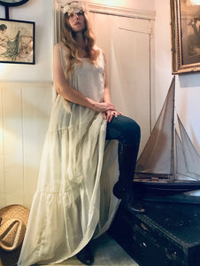 A quirky look - a hippy girl wears a long white flowing dress over jeans and boots 