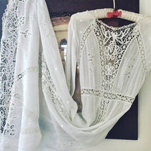 An original Edwardian white cotton lace is shown hung on a hanger. The dress has lace inserts at the bodice, hem, skirt and cuffs.  