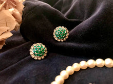 1950's diamante and green paste earrings - a dome of glittering green stones is surrounded by a circlet of twinkling white diamantes. The clip on earrings are shown against a black velvet background with pearls and dried hydrangeas