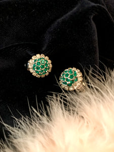 a pair of faux emerald vintage clip on earrings from the 1950's sparkle against black velvet and peachy feathers