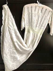 A stunning Edwardian white dress is shown on the hanger. The dress is extravagantly worked with broderie anglais and handmade lace, and is a beautiful example of the period. Perfect for a wedding gown. 
