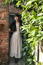 A pretty girl peers through a garden doorway. She is wearing 1940's separates made in shell pink lace. An antique black lace headband and cape complete the Bloomsbury style look. 