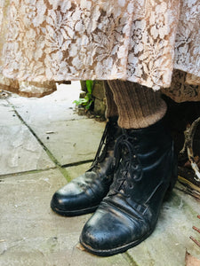 A close up of the soft pink lace at the hem of the skirt is shown , you can see that the vintage forties skirt is being worn with black lace up boots and woollen socks 