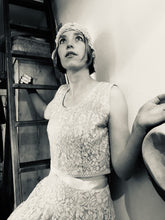 A black and white photo of a girl posing on a ladder wearing a 1940's wedding outfit - the separates appear like a dress when worn together, creating a Bloomsbury style wedding outfit 