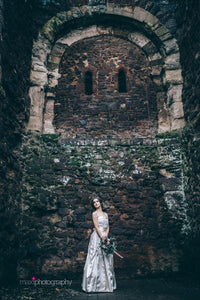 The ivy covered walls of Exeter castle loom above a bride in an oyster satin 1950's vintage wedding dress. The original vintage 50's dress has ruching and a bell skirt